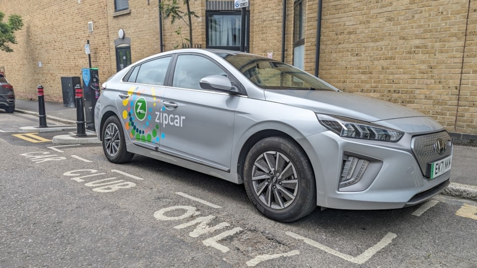 Image of a Hyundai IONIQ car with the Zipcar logo on the side parked in a car club parking bay.